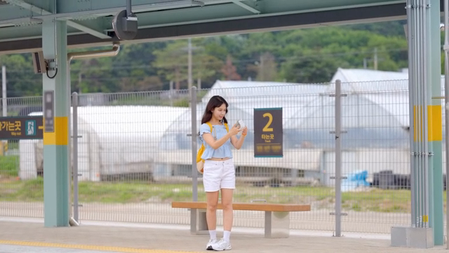 A young woman taking selfies at a train station