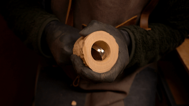 Artisan refining wood carving holes with curved chisel