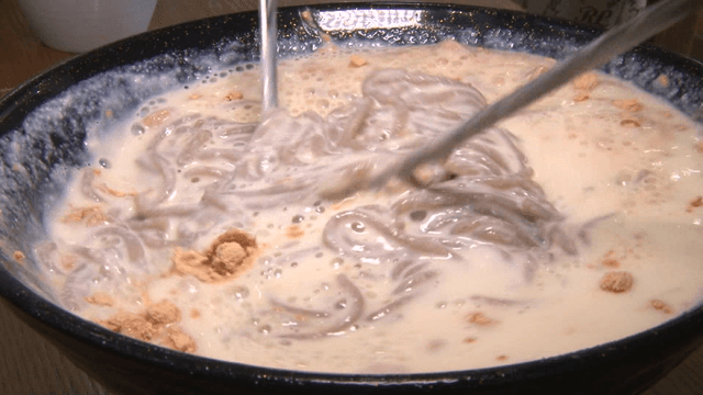 콩가루가 뿌려진 콩국수가 젓가락으로 섞이는 장면