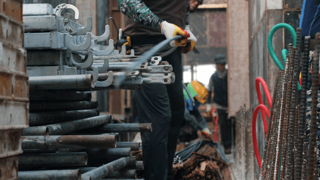 Workers handling metal pipes at a construction site