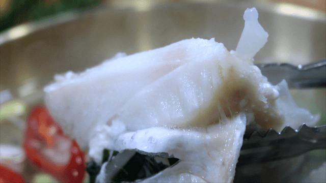 Tongs lifting cod soup fillet