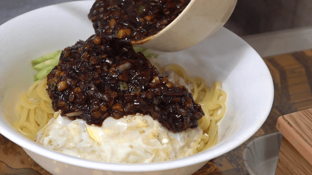 Pouring sauce over black bean noodles