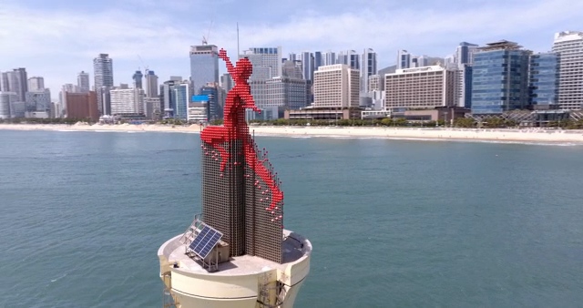A red statue near a coastal city skyline