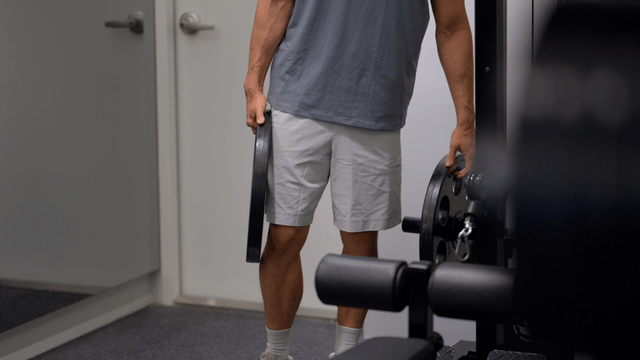 Man loading weight plates onto gym machine