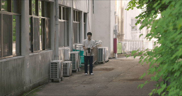 Person holding a camera in an alley
