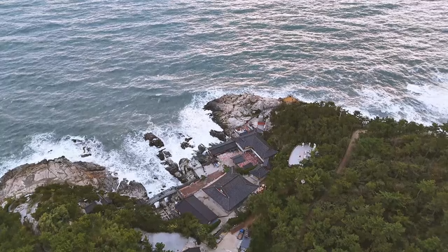 Coastal temple and rough sea under cloudy skies