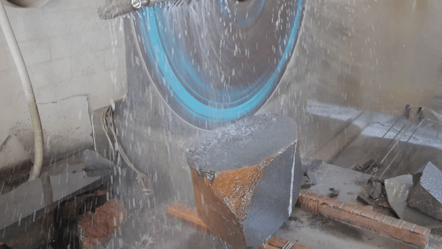 Water-spraying industrial saw cutting a large stone