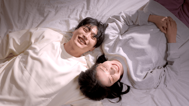 Couple playfully smiling on bed