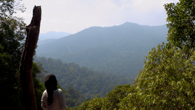 A person posing against a mountain backdrop