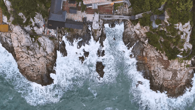Waves striking the coastal cliff with a seaside temple