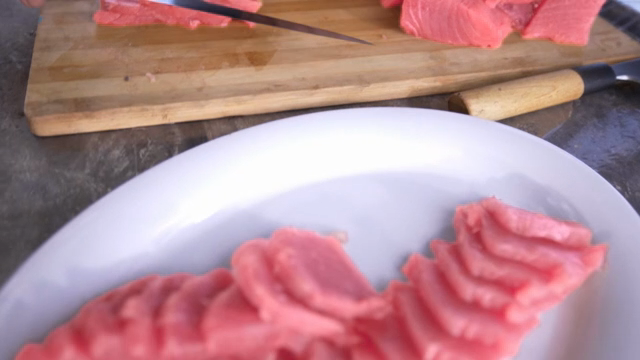 Slicing fresh tuna on a wooden board