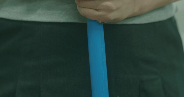 Person holding a blue stick indoors