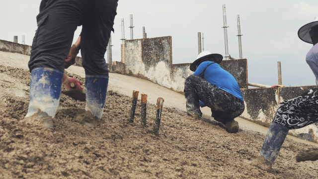 Workers smoothing wet concrete on a slope