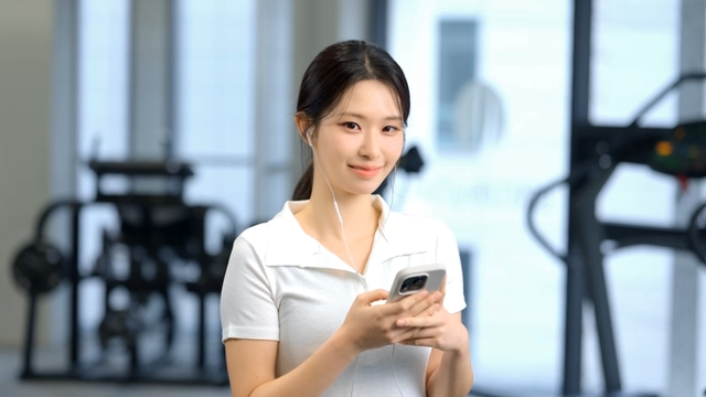 Woman using smartphone with earphones at gym