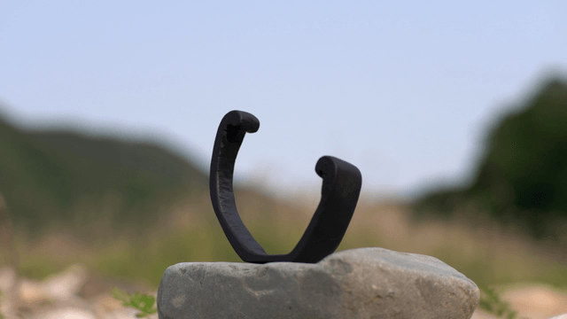 Black wooden sculpture on rock in nature