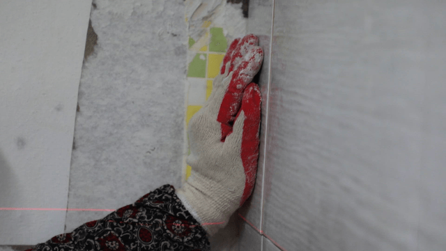 Worker applying adhesive to tiles