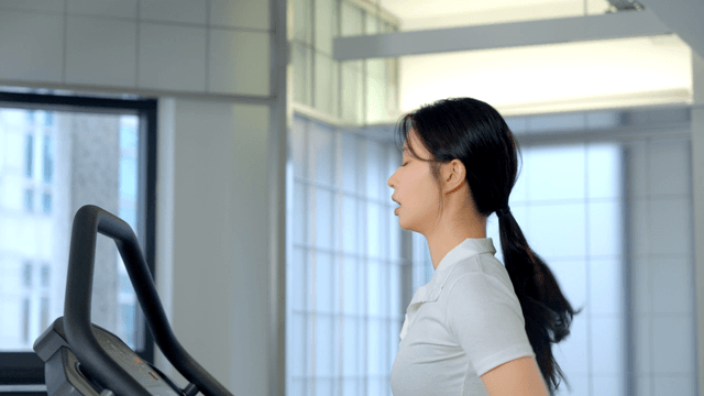 Side view of woman running on treadmill