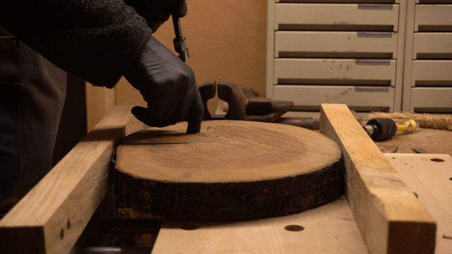 Carpenter drilling a hole in a wooden board at workshop