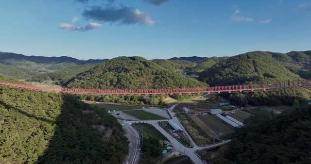 A red bridge spanning lush green mountains