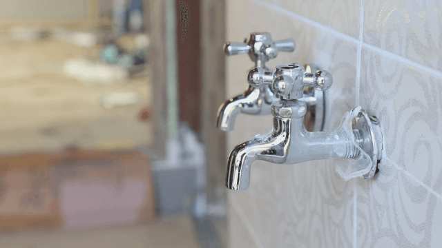 Chrome faucets on a tiled wall