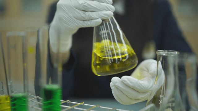Student handling a yellow liquid in a lab
