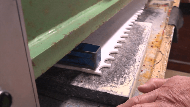 Worker operating fabric cutting machine in factory