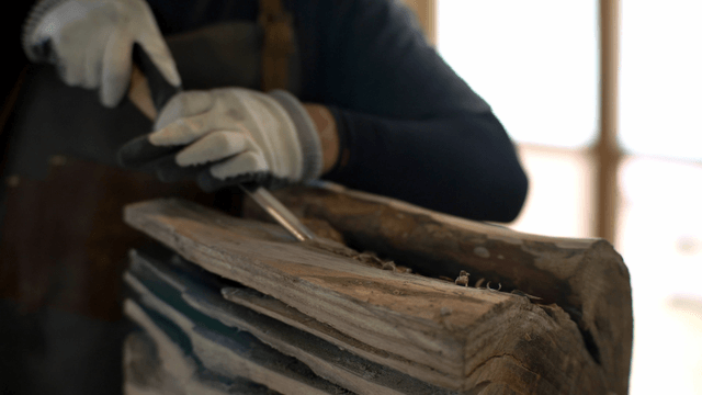Woodcraft artisan carving wood forcefully with a chisel