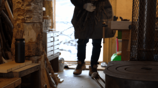 Person carrying wooden branches into a carpentry workshop