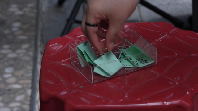 A hand placing a note into a box