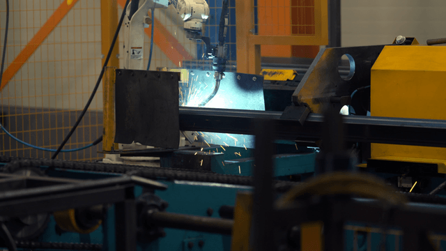 Robotic arm welding metal in a factory