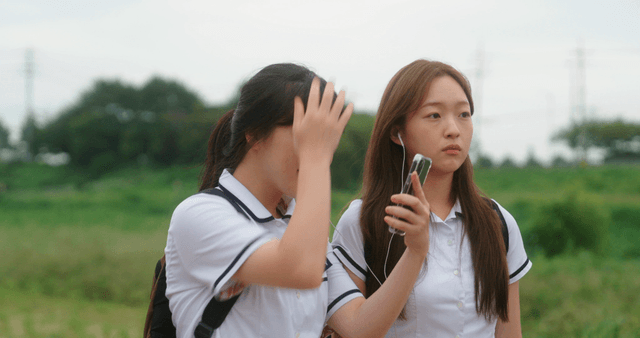 Two students walking by the riverside trail sharing earphones