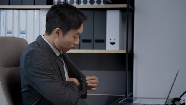 A man sitting at his office desk and turning on his laptop