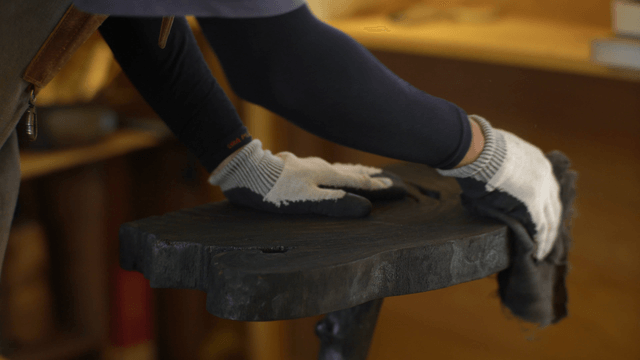 Polishing a wooden stool indoors