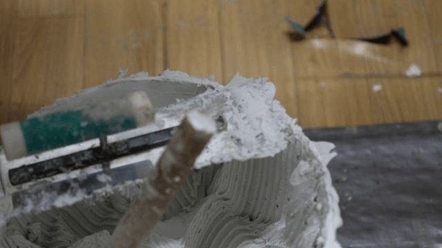 Bucket of adhesive with a mixing tool