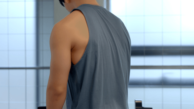 Young man sitting on a leg workout machine at gym