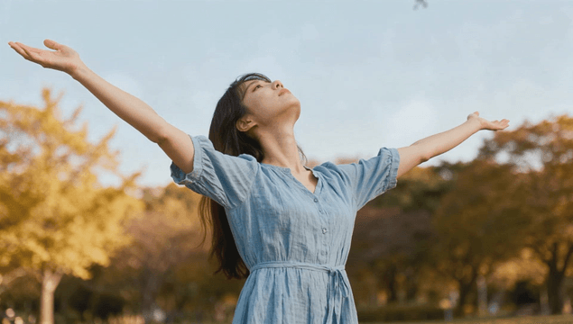 Young woman enjoying sunlight in autumn park