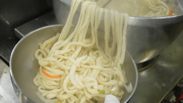 Transferring noodle soup into a bowl