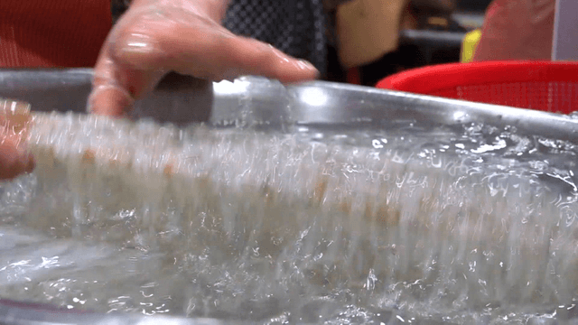 Chopsticks lifting ice fish from basin of water