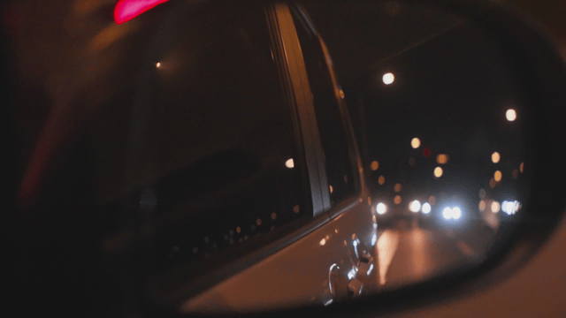 Faint night road view seen through a car side mirror