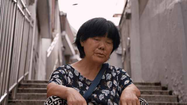 계단에 앉아 숨을 몰아쉬는 노인 여성
