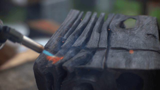 Blowtorch burning wood in outdoor workshop