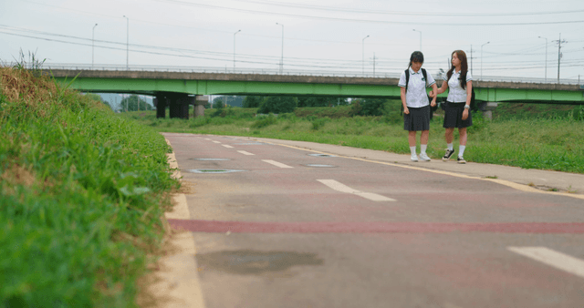 Two students walking by the riverside trail sharing earphones