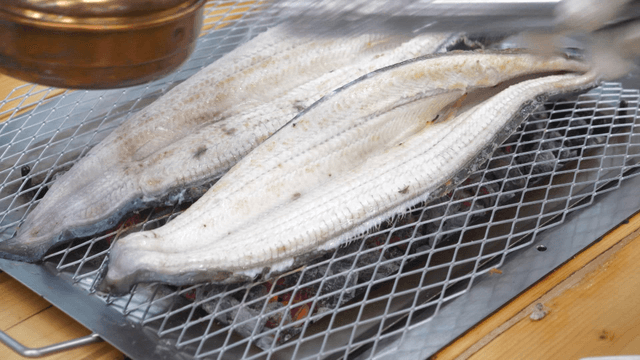 Large eel cooking over charcoal fire