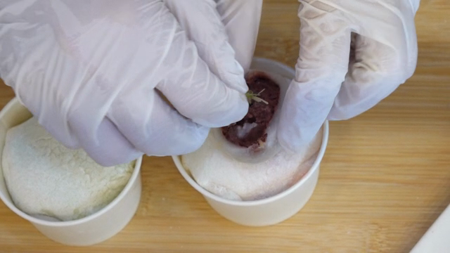 Gloved hands preparing mochi dessert