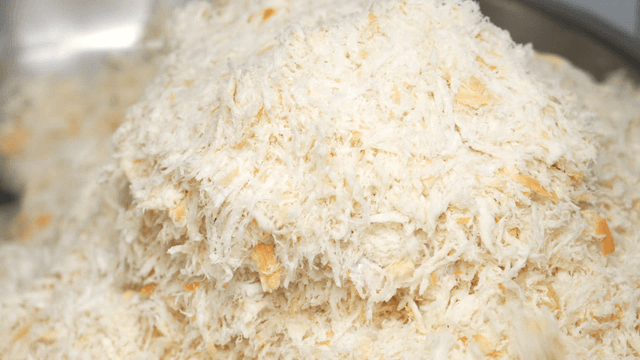 Gloved hands breading meat