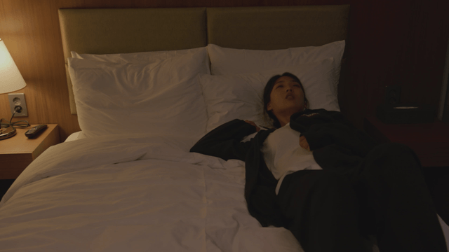 Woman resting on a bed in a dimly lit room