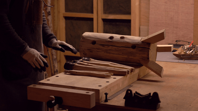 Craftsman working with wooden logs indoors