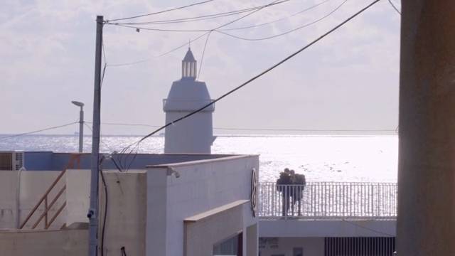 Lighthouse by the sea with people on a balcony