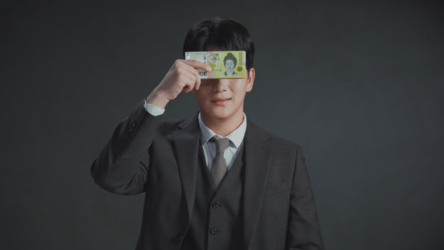 Man smiling with his eyes covered by money