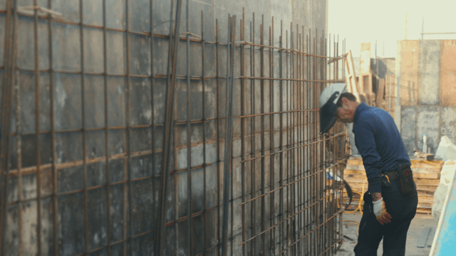 Construction worker inspecting rebar wall
